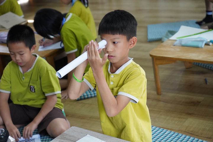 เด็กมองผ่านท่อกระดาษเห็นรูกลางฝ่ามือ